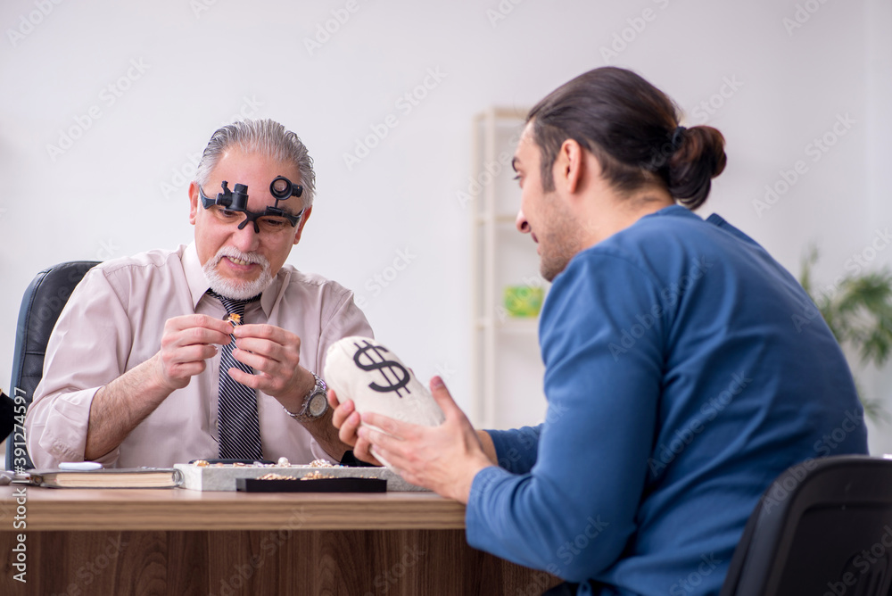 Young man visiting old male jeweler