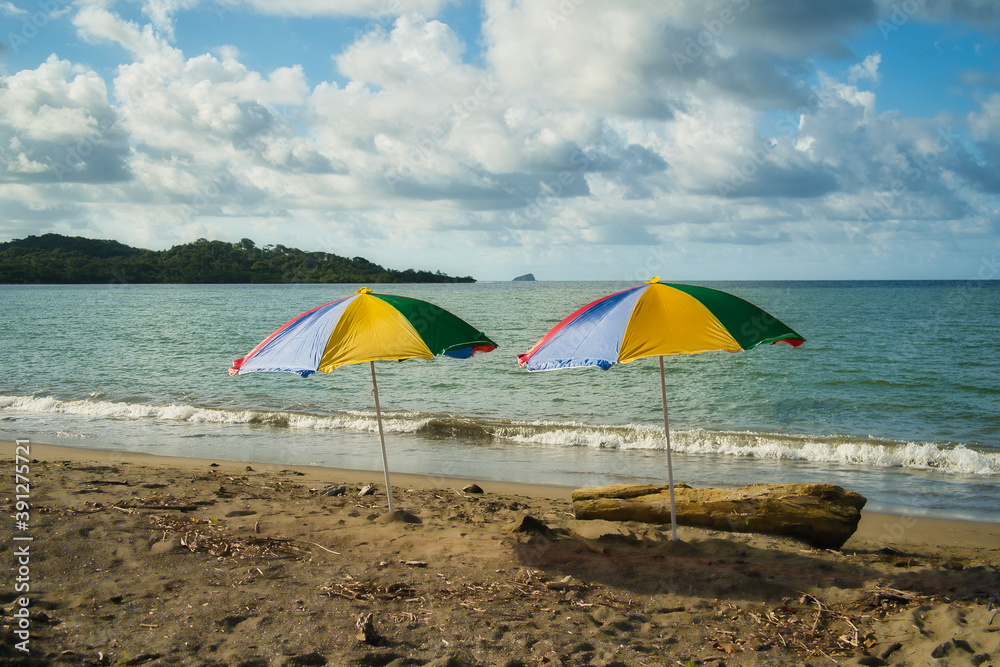 Zwei bunte Sonnenschirme am einsamen Naturstrand in Panama am karibischen Meer, baden, schnorcheln und Kraft tanken
