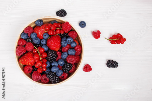 Canvas Print Mix of berries in bowl on white wooden background