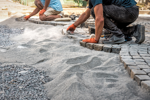Canvas Print two workers lays a stone pavement