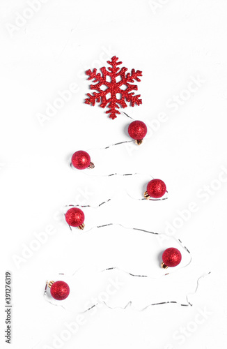 Christmas tree made of shiny ribbon, red baubles and snowflake on white. Top view. Stylized Christmas tree