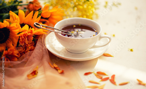 Autumn, fall leaves, flowers hot cup of herbal tea on wooden rustic background. Seasonal, morning tea. Sunday relaxing and still life concept. Toned image.