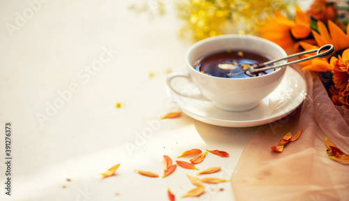 Autumn, fall leaves, flowers hot cup of herbal tea on wooden rustic background. Seasonal, morning tea. Sunday relaxing and still life concept. Toned image. Copy space.