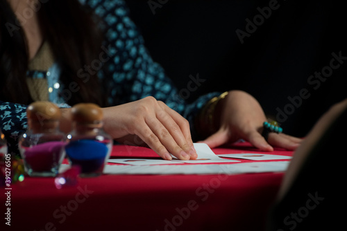 Close up Gypsy fortune teller woman in dark room with white tarot card