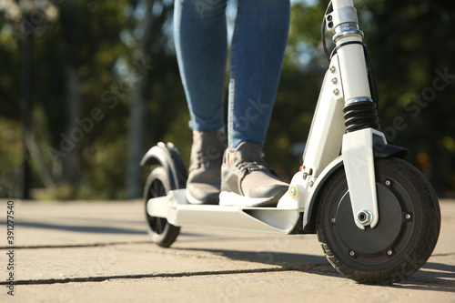 Woman riding electric kick scooter outdoors, closeup photo