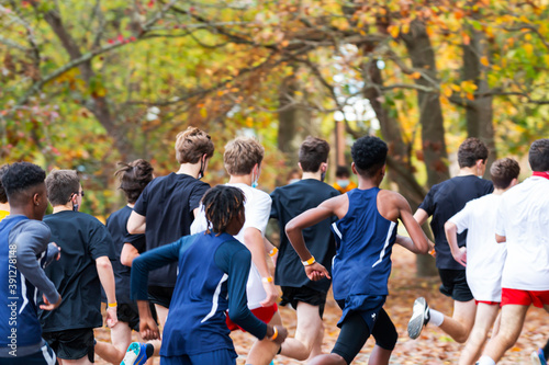 Boys running a race with autumn colored leaves on the ground and the trees