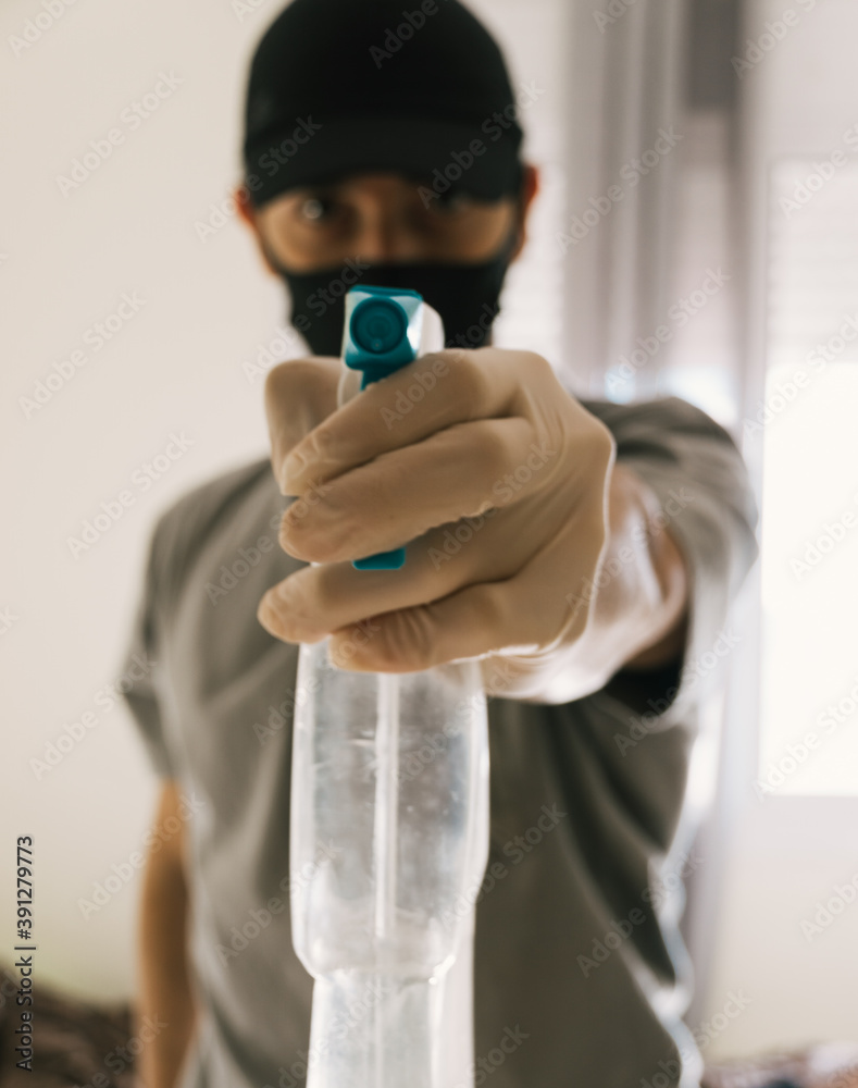 Man pointing disinfectant spray at camera. He is wearing an  anti-contamination mask because of the covid-19. Focus on the spray. Stock  Photo | Adobe Stock