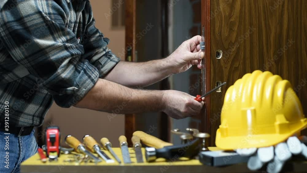 Close-up. Carpenter with screwdriver fixes the lock of a wooden door. Construction industry. Footage. Close-up. Carpenter with screwdriver fixes the lock of a wooden door. Construction industry. Footage.