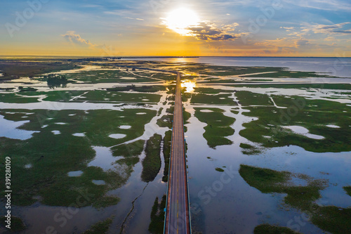 Aerial view of highway during sunrise in the middle of  swamp