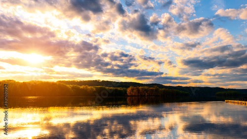 Landscape view of Mississippi river  at Wisconsin Minnesota border with cloud reflection on water surface and warm sun light and trees, forest beside the river.