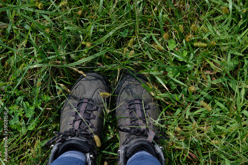 Looking down at brown hiking boots standing in the grass on a trail