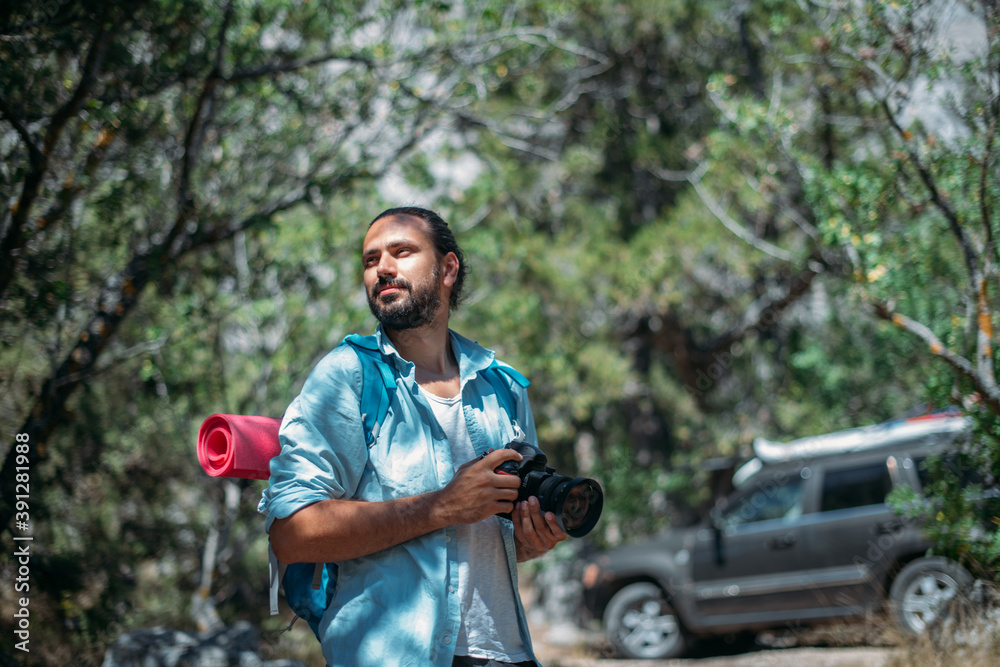Male photographer with a camera on a hike by car