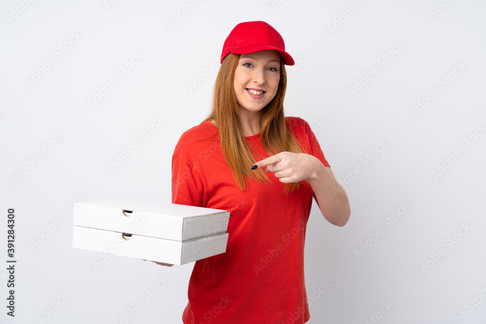 Pizza delivery woman holding a pizza over isolated pink wall and pointing it Pizza delivery woman holding a pizza over isolated pink wall and pointing it