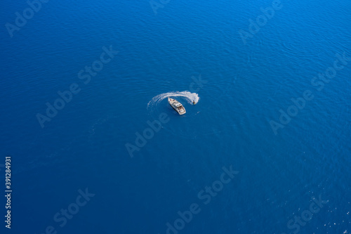 Water scooter movement close to the yacht aerial view.High-speed yacht of white color on blue water in the rays of the sun top view. Yachts at the sea surface.