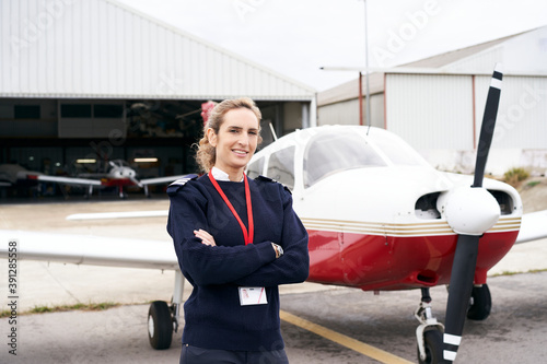 Young female pilot posing smiling in front of her plane. photo