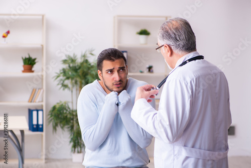 Young sick man visiting old doctor