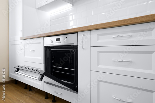 Modern cooking stove in white kitchen interior with tiled wall and wooden countertop