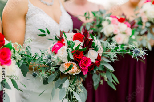 Bride and her Bridesmaids with her wedding bridal bouquet with red and white roses and greenery