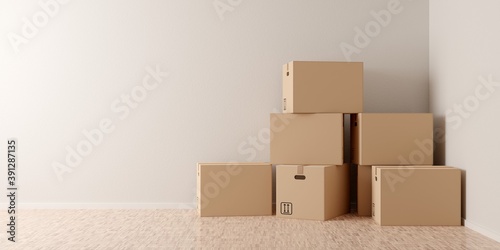 Brown moving storage cardboard boxes stacked in empty room in apartment or house with wooden floor with copy space © Shawn Hempel