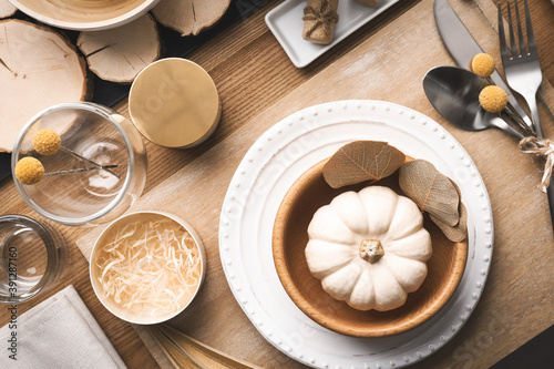 Autumn table setting with pumpkin and decor on wooden background, flat lay