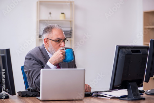 Old male boss sitting at desktop in the office