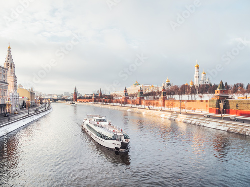 View on touristic ship going down Moscow-river, Kremlin walls and bell tower of Ivan the Great. Winter sunset in historical center of Moscow, Russia.