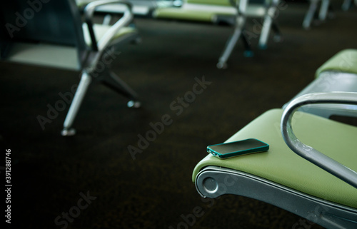 Smartphones forgotten on the seat, Mobile phone put forgotten ,Smartphone with an on the seat of a international airport ,Concept of mobile communication in travel and lost gadgets in the airport,