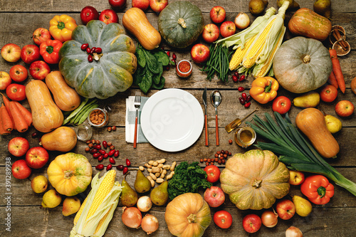 Plate with cutlery surrounded with assortment of vegetables on wooden board