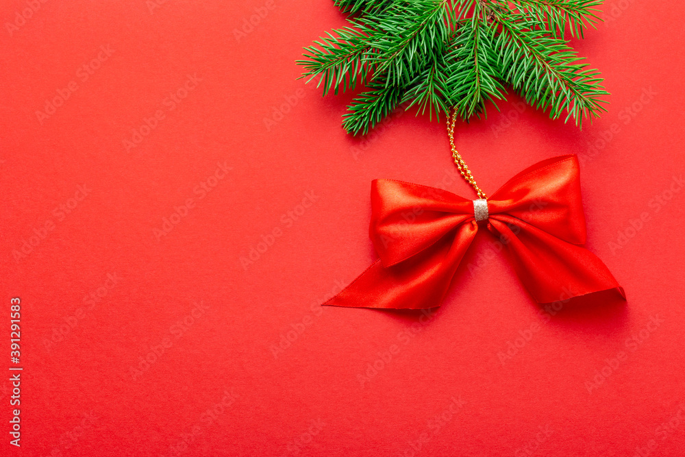 Red Christmas bow hanging from the spruce on top on red background