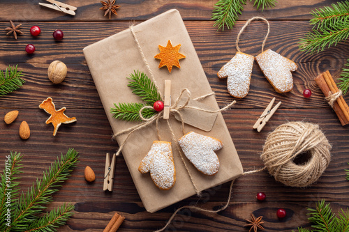 Vintage Christmas present decorated with mitten-shaped cookies and spruce branches tied by jute twine