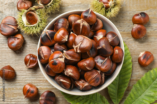 Delicious roasted edible chestnuts on wooden table, flat lay