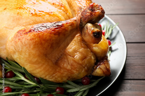 Delicious cooked turkey served with rosemary and cranberries on wooden table, closeup. Thanksgiving Day celebration