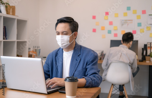 Asian workers in offices wear face masks to prevent the spread of COVID-19. Working in the new normal era and Social distance.