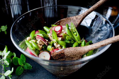Salad with sugar snap pea, radishes and mint in glass bowl