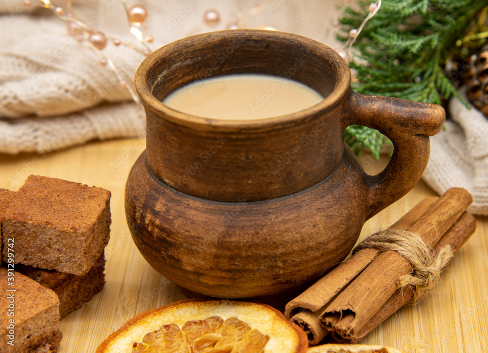 A clay mug with a drink and various Goodies are on a wooden tray, standing on a knitted blanket . A clay mug with a drink and various Goodies are on a wooden tray, standing on a knitted blanket .