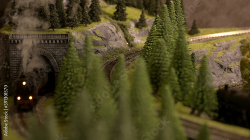 Model of retro railway. Lokomotive with steam and trees. photo