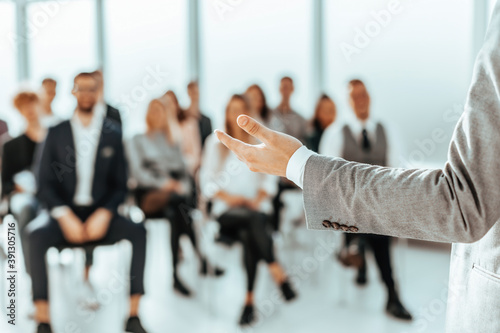 background image of a speaker standing in front of listeners in a conference room