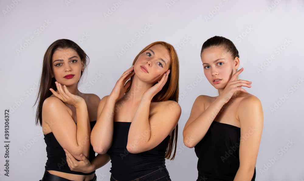 Three cute and attractive girls posing on a gray background in the studio. Spa and body beauty concept. Body and care Three cute and attractive girls posing on a gray background in the studio. Spa and body beauty concept. Body and care
