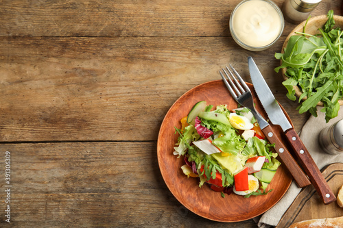 Delicious salad with lettuce served on wooden table, flat lay. Space for text