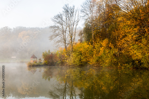 Beautiful landscape with lake and forest. Amazing nature wallpaper. Autumn trees in foggy morning. Romantic place. 