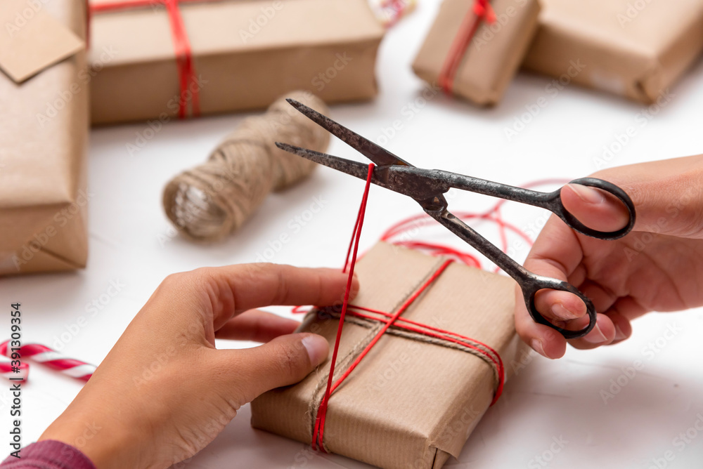 Female's hands wrapping Christmas gift boxes decorated with kraft paper