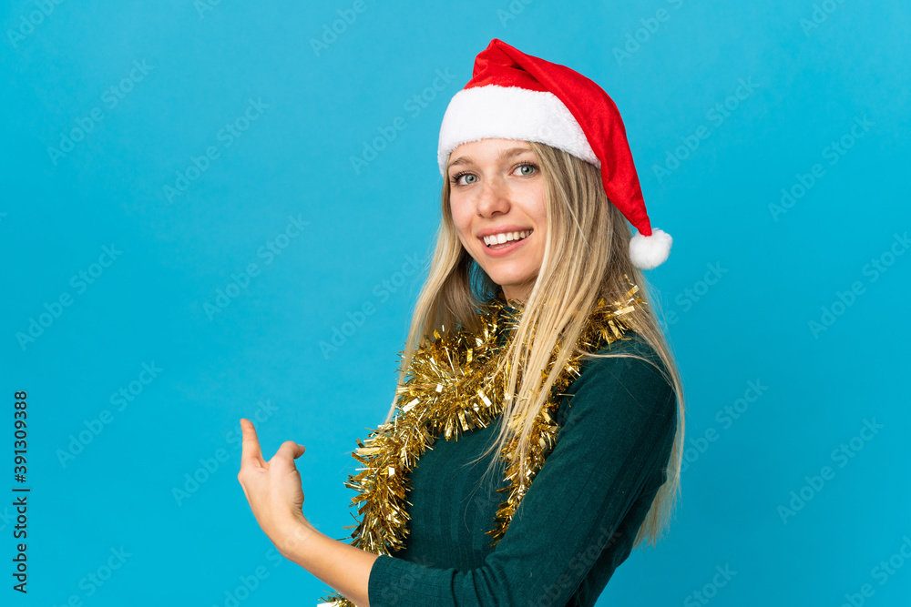 Woman with christmas hat isolated on blue background pointing back Woman with christmas hat isolated on blue background pointing back