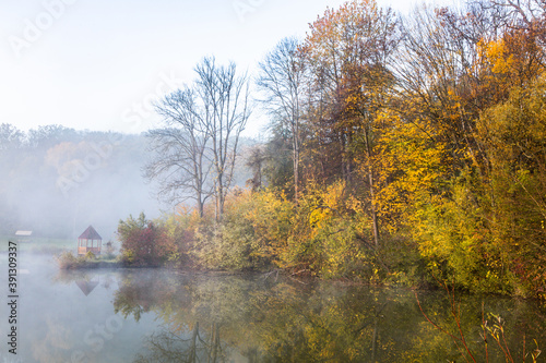 Beautiful landscape with lake and forest. Amazing nature wallpaper. Autumn trees in foggy morning. Romantic place. 