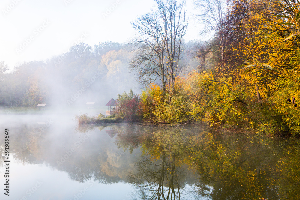 Beautiful landscape with lake and forest. Amazing nature wallpaper. Autumn trees in foggy morning. Romantic place. 