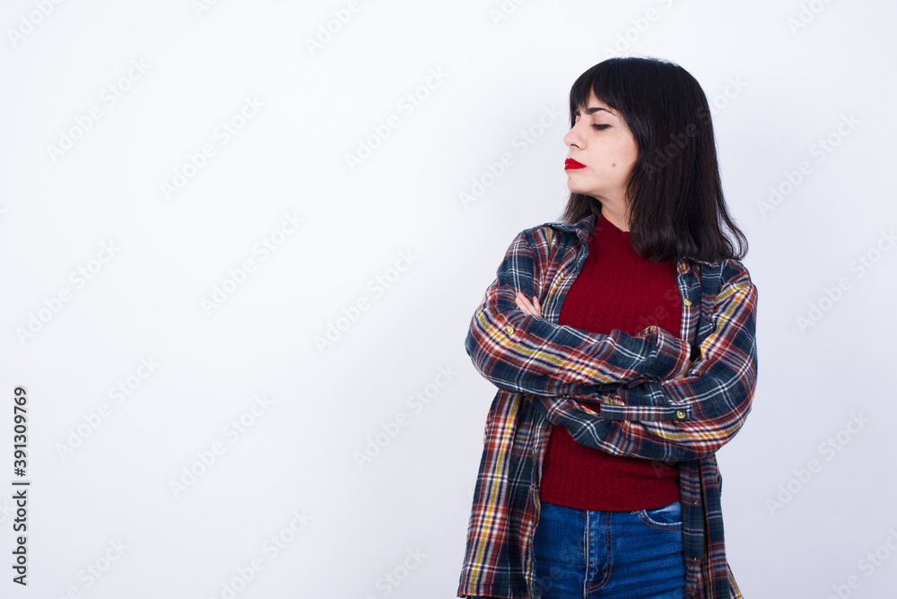 Image of upset Beautiful young Caucasian woman standing against white background with arms crossed. Looking with disappointed expression aside after listening to bad news. Image of upset Beautiful young Caucasian woman standing against white background with arms crossed. Looking with disappointed expression aside after listening to bad news.