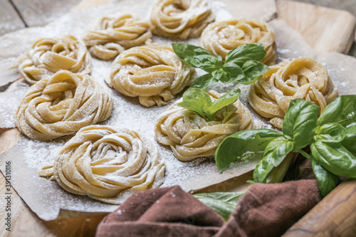 Pasta alluovo, Tagliatelle or fettuccine. Round balls of raw pasta on the wooden cutting board on black background photo