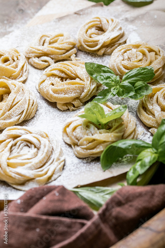 Pasta alluovo  Tagliatelle or fettuccine. Round balls of raw pasta on the wooden cutting board on black background