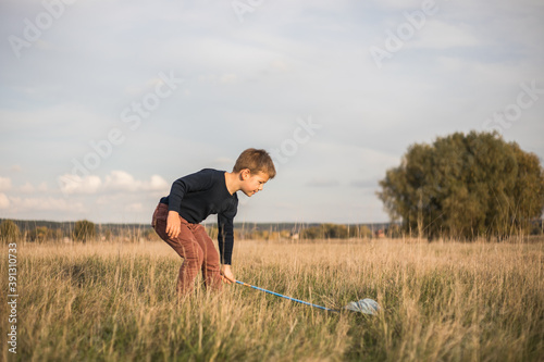 Young boy with butterfly net walking meadow. Child playing catching insects. Seasonal summer activity for kids outdoor. Learning animal fauna world hobby.