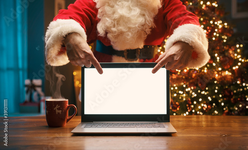 Santa Claus pointing at the laptop screen