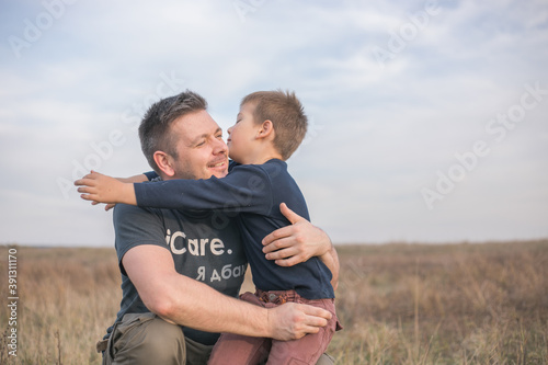 Happy son hugging dad on the  meadow background. Concept of father-son relationship © Maria